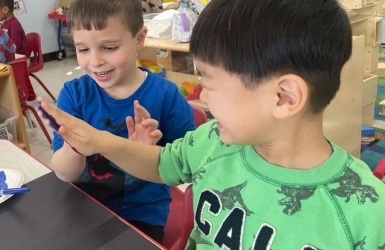 Two kids sitting at a table smiling