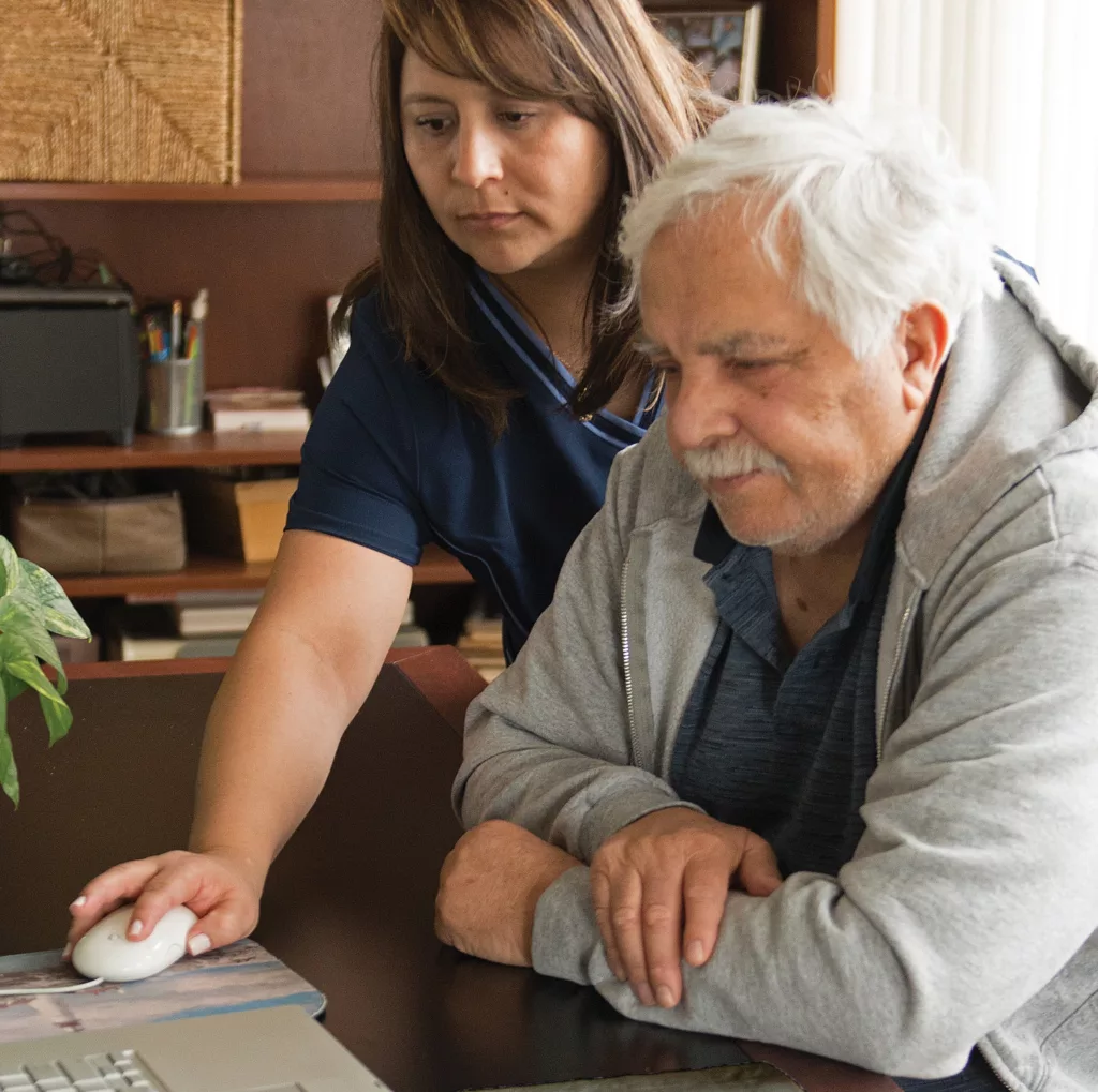 Elderly man getting assistance from a woman in front of a computer